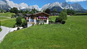 Charmantes Haus in alpiner Landschaft mit blühenden Balkonen und beeindruckendem Bergblick.