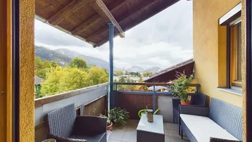 Gemütlicher Balkon mit Sitzgelegenheiten und herrlichem Bergblick unter einem Holzdach.