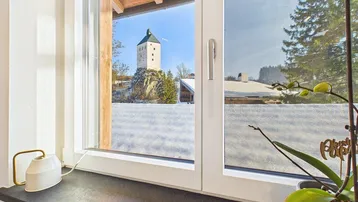 Fensterblick auf einen historischen Turm und die verschneite Winterlandschaft.