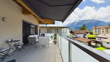 Geräumige Terrasse mit bequemen Loungemöbeln, Sonnenschutz und beeindruckendem Bergblick.