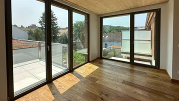 Lichtdurchfluteter Wohnraum mit Holzboden, Holzdecke und weitem Blick durch große Fenster.