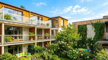 Moderne Wohnanlage mit üppigem Garten, mehreren Balkonen und gemütlichen Sitzbereichen im Freien.