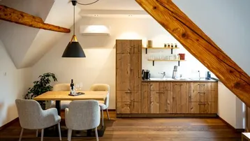 Moderne Holzküche im Dachgeschoss mit Essbereich, Holzbalken und Dachfenster für natürliches Licht.