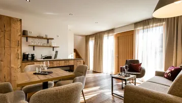Helles, offenes Wohnzimmer mit integrierter Holzküche, Esstisch und Zugang zur Terrasse.