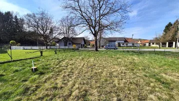 Weitläufiges Grundstück mit Grasfläche und Blick auf die umliegende ländliche Bebauung unter blauem Himmel.