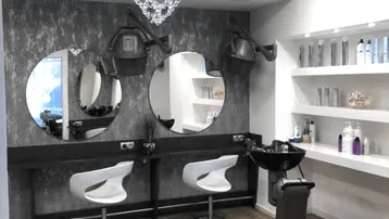 Moderner Friseursalon mit mehreren Styling-Stationen, Waschbecken und Produktregalen in stilvollem Ambiente.