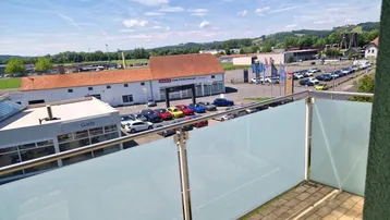 Geräumiger Balkon mit Milchglasbrüstung und Blick auf die umliegende Gewerbezone und Hügellandschaft.