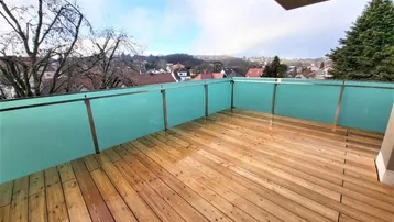 Geräumiger Balkon mit Holzboden und moderner Glasbrüstung, bietet einen weiten Blick über die Umgebung.