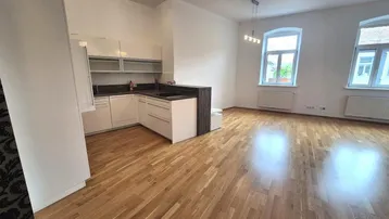 Heller offener Wohn-Essbereich mit moderner Einbauküche, Holzboden und großen Fenstern.