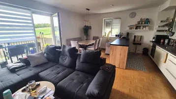 Geräumiger offener Wohn- und Essbereich mit moderner Küche und Zugang zum Balkon mit Weitblick.