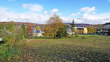 Weitläufiges Grundstück mit herbstlicher Vegetation und Panoramablick auf die umliegende Siedlung und Hügel.