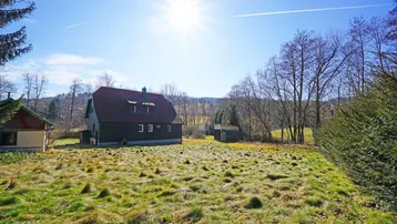 Ländliches Anwesen mit großem Grundstück und sonniger Lage, umgeben von Bäumen und Hügeln.