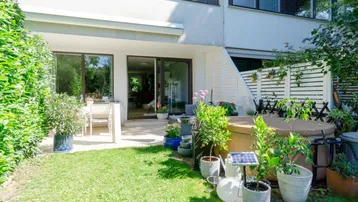 Gepflegter Gartenbereich mit Rasenfläche, Terrasse und Whirlpool vor dem Haus.
