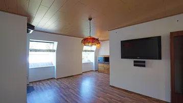 Wohnbereich mit Laminatboden, Holzdecke und zwei Dachfenstern für natürliches Licht.