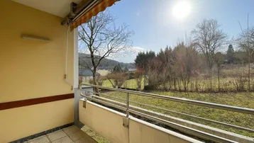 Sonniger Balkon mit Markise und weitem Blick ins Grüne und auf die umliegende Landschaft.
