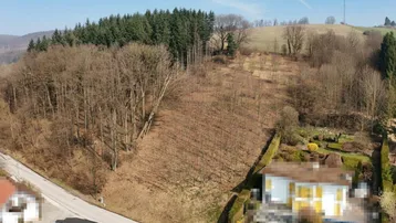 Luftaufnahme des Anwesens, umgeben von Wäldern und einer ländlichen Hügellandschaft mit einer Straße.