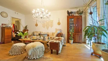 Helles Wohnzimmer mit Holzboden, Kronleuchter und gemütlichen Sitzgelegenheiten, reich an Dekoration.