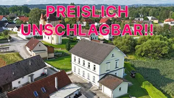 Luftaufnahme eines traditionellen Hauses in grüner, ländlicher Umgebung, beworben als 'PREISLICH UNSCHLAGBAR!!'.