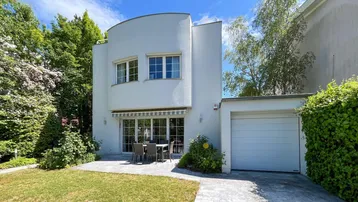 Moderne weiße Villa mit gepflegtem Vorgarten, Terrasse und integrierter Garage.