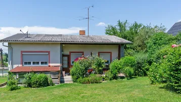 Einfamilienhaus mit gepflegtem Gartenbereich und grüner Umgebung unter blauem Himmel.