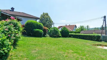 Weitläufiger Garten mit Rasenfläche, Hecken und Blick auf die umliegende Landschaft.