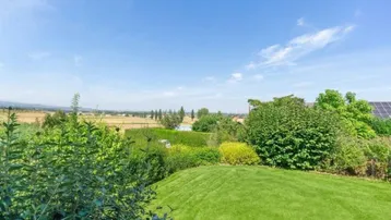 Weitläufiger Gartenbereich mit üppigem Grün und einem malerischen Blick auf die umliegende Landschaft.