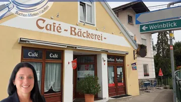 Außenansicht eines Gebäudes mit Café- und Bäckereischild, umgeben von Bäumen und einem Straßenschild.