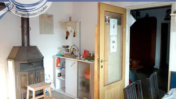 Essbereich mit Holzofen, kleinem Schrank und Zugang zu einem weiteren Raum.
