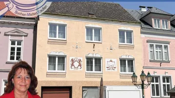Historische Fassade eines Mehrfamilienhauses mit dekorativen Elementen und großen Fenstern.