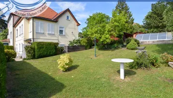 Gepflegter Gartenbereich mit Rasenfläche und einem kleinen Tisch vor dem Haus.