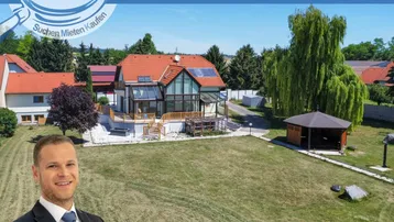 Großzügiges Anwesen mit weitläufigem Garten, Wohnhaus und Gartenlaube unter blauem Himmel.