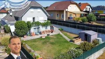 Blick auf das Einfamilienhaus mit gepflegtem Garten und Rasenfläche, umgeben von weiteren Wohnhäusern.