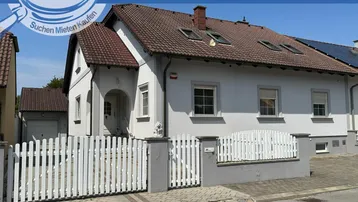 Attraktives Einfamilienhaus mit weißer Fassade, Satteldach und gepflegtem Vorgartenbereich.