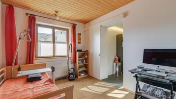 Schlafzimmer mit Holzbalkendecke, Holzboden und Blick ins Grüne.