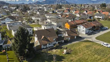 Weitläufige Luftaufnahme der Wohngegend mit Häusern und Bergen im Hintergrund.