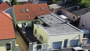 Luftaufnahme eines Wohnhauses mit Garage und umliegenden Gebäuden in einer Wohngegend.