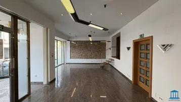 Großer, heller Gewerberaum mit poliertem Steinfußboden, einer Natursteinwand und modernen Deckenleuchten.