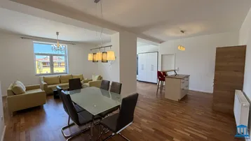 Geräumiger offener Wohn- und Essbereich mit Holzboden, beigen Sofas und einem Esstisch.