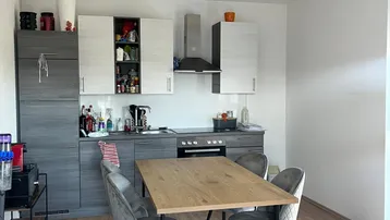Moderne Wohnküche mit Essbereich, grauen Schränken und Holzfußboden, gut beleuchtet.