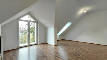 Geräumiges Zimmer im Dachgeschoss mit Laminatboden, schräger Decke und Zugang zu einem französischen Balkon.