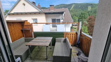 Gemütlicher Balkon mit Sitzgelegenheiten, Holzsichtschutz und Bergblick.