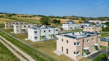 Weitläufige Ansicht einer Neubausiedlung eingebettet in die ländliche Landschaft.