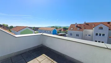 Geräumige Dachterrasse mit Fliesenboden und weitem Blick über die Nachbarschaft und Hügel.