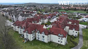 Weitläufige Luftaufnahme eines Wohngebiets mit mehreren Gebäuden und ländlicher Umgebung.