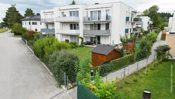 Moderne Wohnanlage mit gepflegten Gärten, Spielplatz und Balkonen in grüner Umgebung.