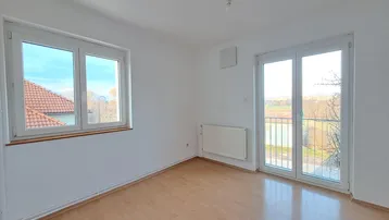 Helles Zimmer mit Parkettboden, weißen Wänden und Zugang zu einem französischen Balkon mit Aussicht.