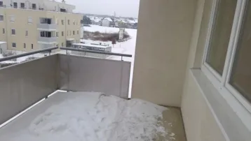 Balkon mit Schnee bedeckt, bietet einen Blick auf die umliegenden Gebäude und die verschneite Landschaft.