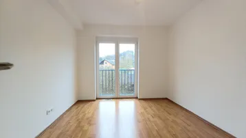 Freundliches Zimmer mit Laminatboden und einem französischen Balkon, bietet viel Tageslicht und Ausblick.