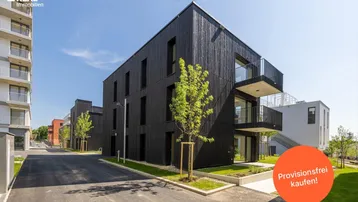 Modernes Wohngebäude mit dunkler Holzfassade und Balkonen in einer neuen Siedlung.