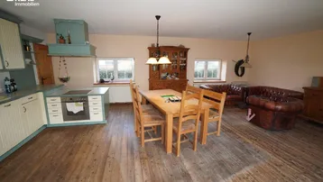 Geräumiger Wohn-Essbereich mit offener Küche, Holzboden und traditionellen Möbeln.